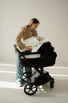 Baby liegt im CosyMe und wird in einen Kinderwagen gelegt